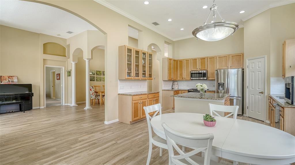 7717 US Open Loop Lakewood Ranch, FL 34202 - Photo 9 of 95 a kitchen with stainless steel appliances a refrigerator a stove top oven a sink dishwasher a dining table and chairs with wooden floor