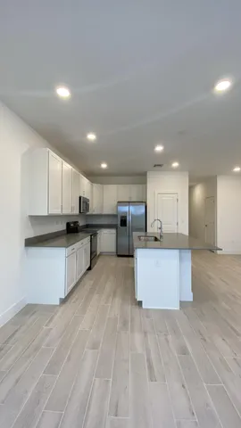 a large white kitchen with kitchen island a sink white cabinets and stainless steel appliances