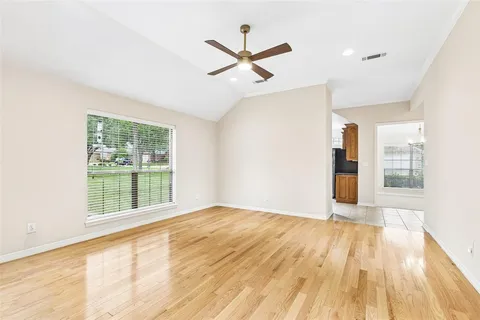 a view of an empty room with wooden floor and a window