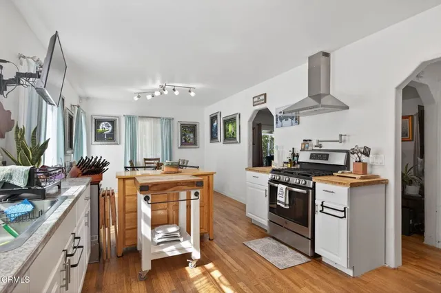 a kitchen with stainless steel appliances a stove a sink dishwasher and cabinets with wooden floor