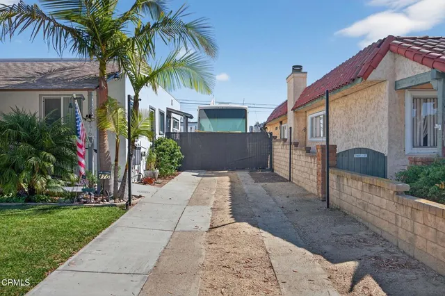a view of a house with a yard and palm trees