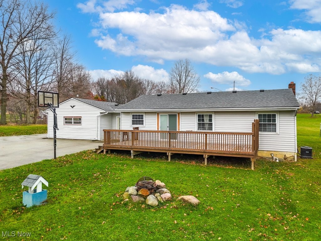 Back of property with a yard, central AC unit, a fire pit, and a deck