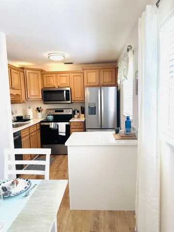 a living room with stainless steel appliances furniture a kitchen view and a refrigerator