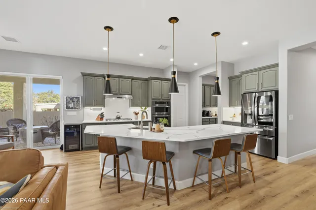 a kitchen with stainless steel appliances kitchen island granite countertop a dining table chairs and white cabinets
