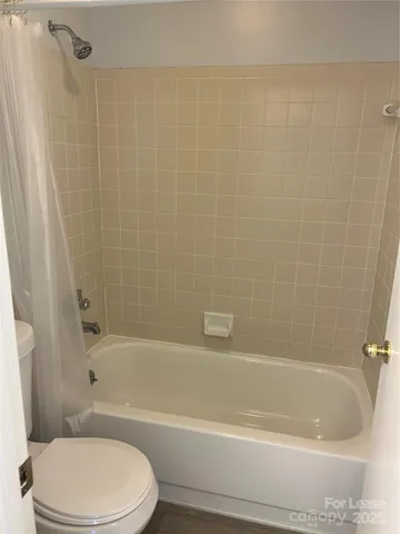 a bathroom with a bathtub shower and toilet