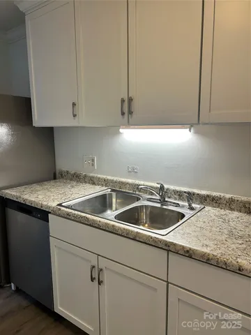 a kitchen with granite countertop white cabinets and a sink