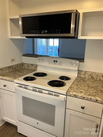 a kitchen with granite countertop white cabinets and white appliances