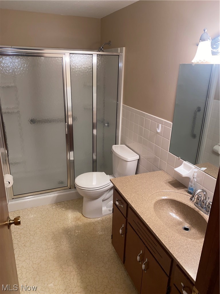 1518 Walnut Road Southwest Massillon, OH 44647 - Photo 10 of 26 Bathroom with vanity, a shower with door, tile walls, and toilet