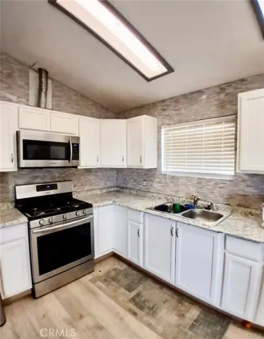 a kitchen with granite countertop a stove sink and microwave