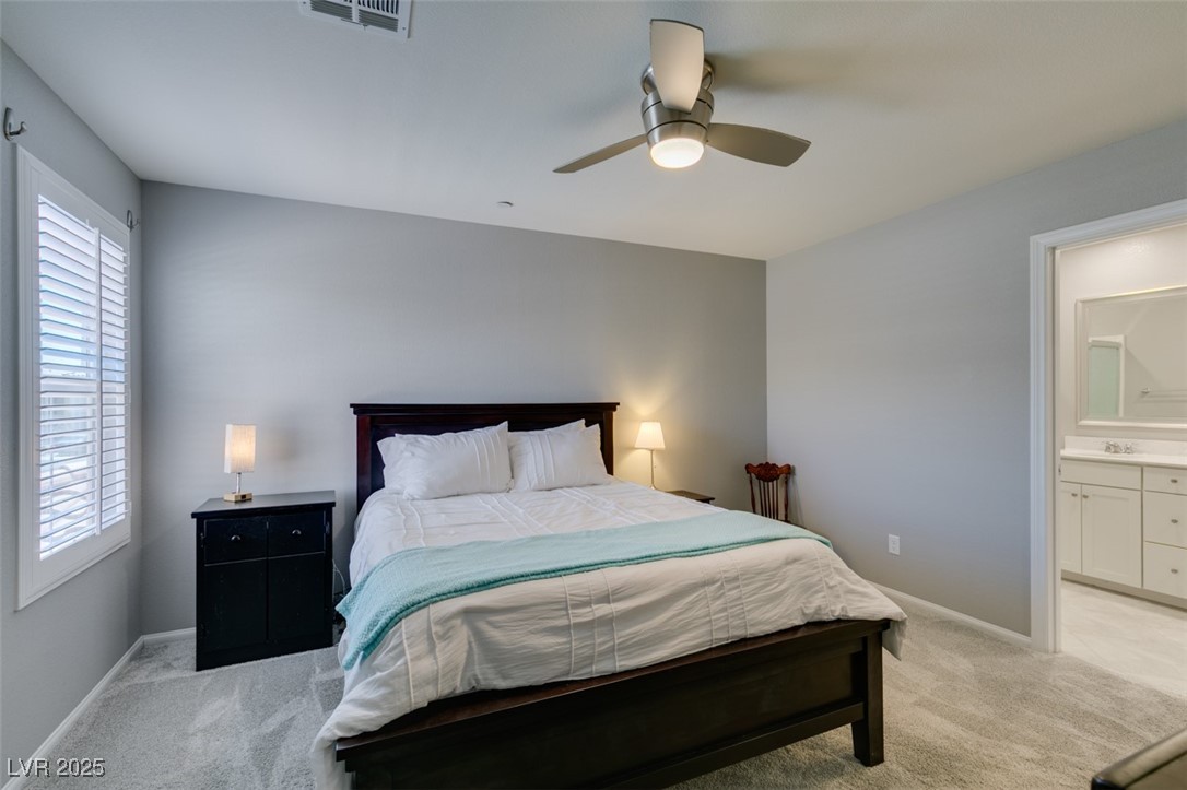 2870 Turnstone Ridge Street Henderson, NV 89044 - Photo 34 of 50 Bedroom with light colored carpet, baseboards, ensuite bath, and a ceiling fan