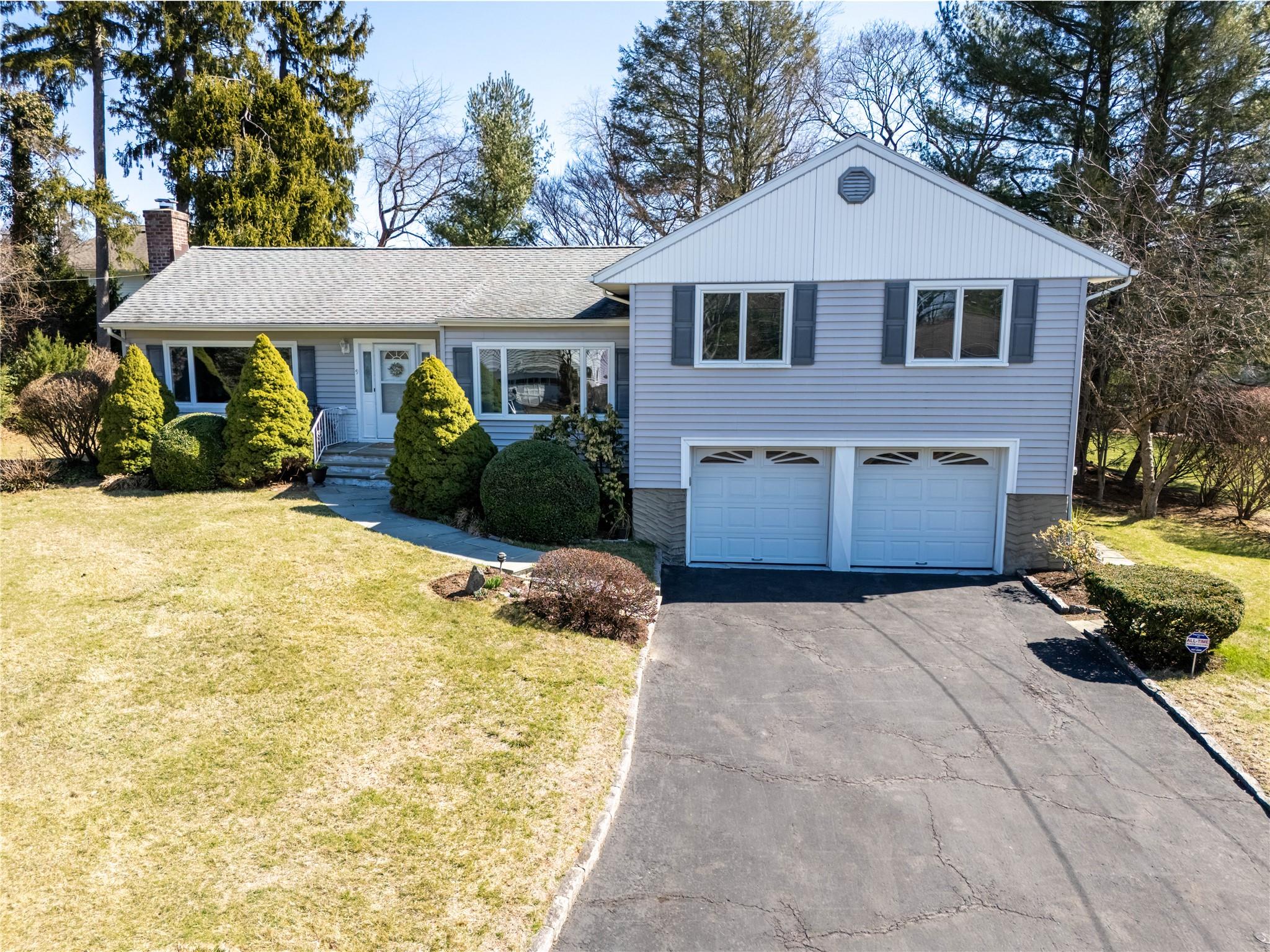 9 Mohegan Lane Rye Brook, NY 10573 - Photo 1 of 1 Split level home with a front lawn, a shingled roof, a garage, and aphalt driveway