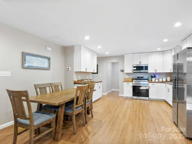 a kitchen with stainless steel appliances a refrigerator a stove a sink a dining table and chairs