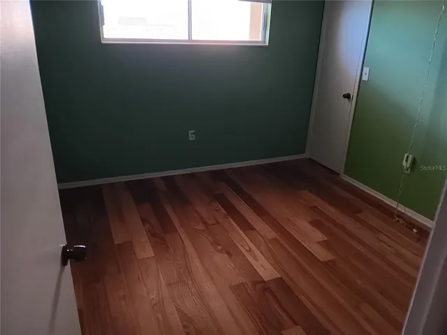 a view of a room with wooden floor and small window