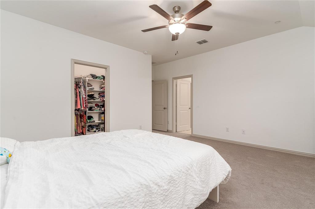 7368 Panicum Drive Frisco, TX 75033 - Photo 22 of 25 Carpeted bedroom with a walk in closet, ceiling fan, a closet, and lofted ceiling