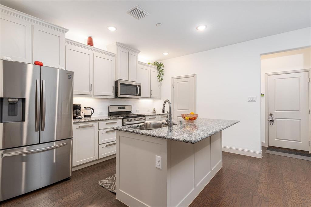 7368 Panicum Drive Frisco, TX 75033 - Photo 8 of 25 Kitchen featuring white cabinets, sink, an island with sink, appliances with stainless steel finishes, and light stone counters