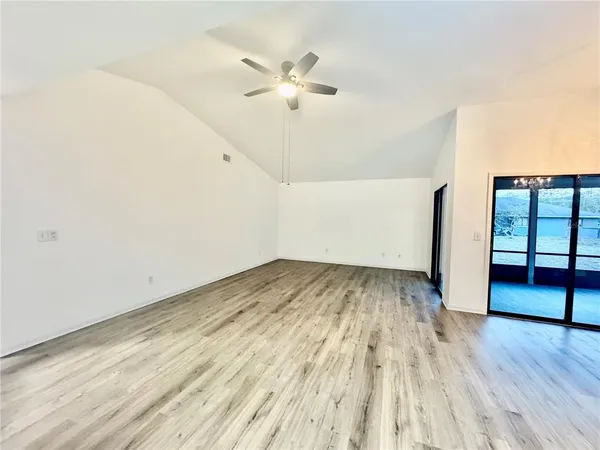 an empty room with wooden floor and ceiling fan