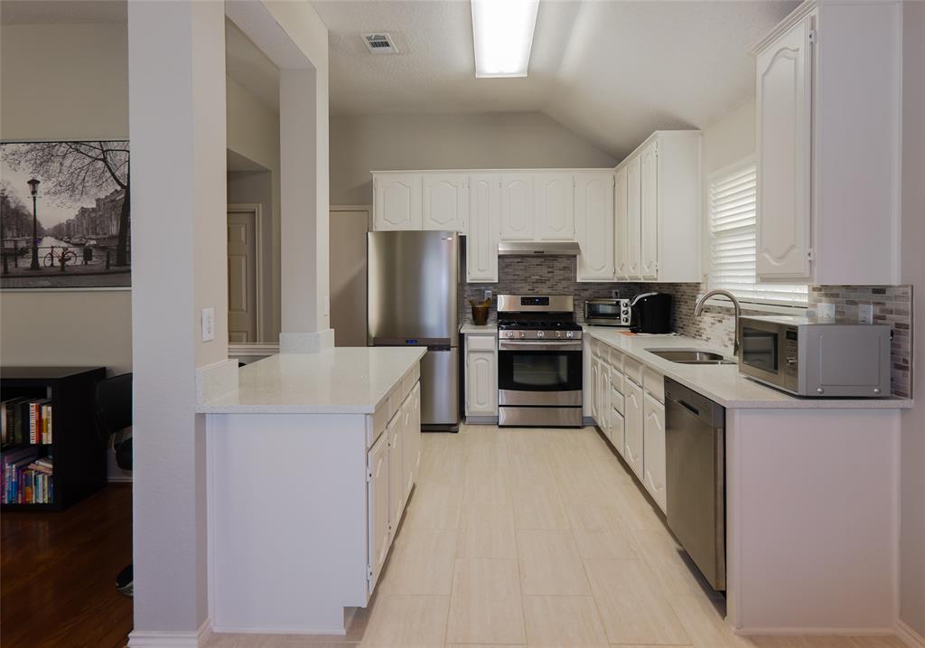 18532 Shadow Ridge Drive Dallas, TX 75287 - Photo 5 of 12 a kitchen with stainless steel appliances a stove a sink a refrigerator a window