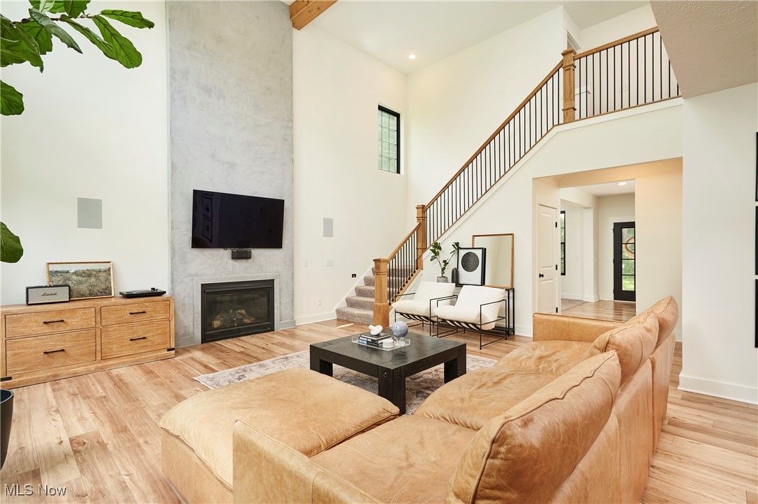 7754 Bainbridge Road Chagrin Falls, OH 44023 - Photo 12 of 35 Living room featuring a fireplace, light wood-style flooring, beam ceiling, a high ceiling, and stairway