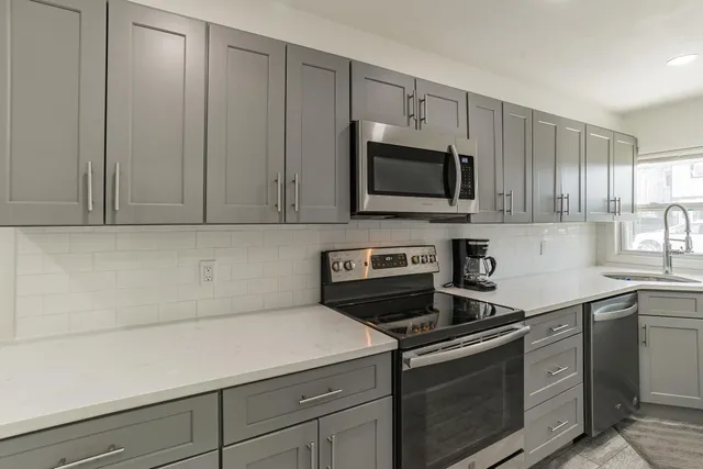 a kitchen with granite countertop white cabinets and stainless steel appliances
