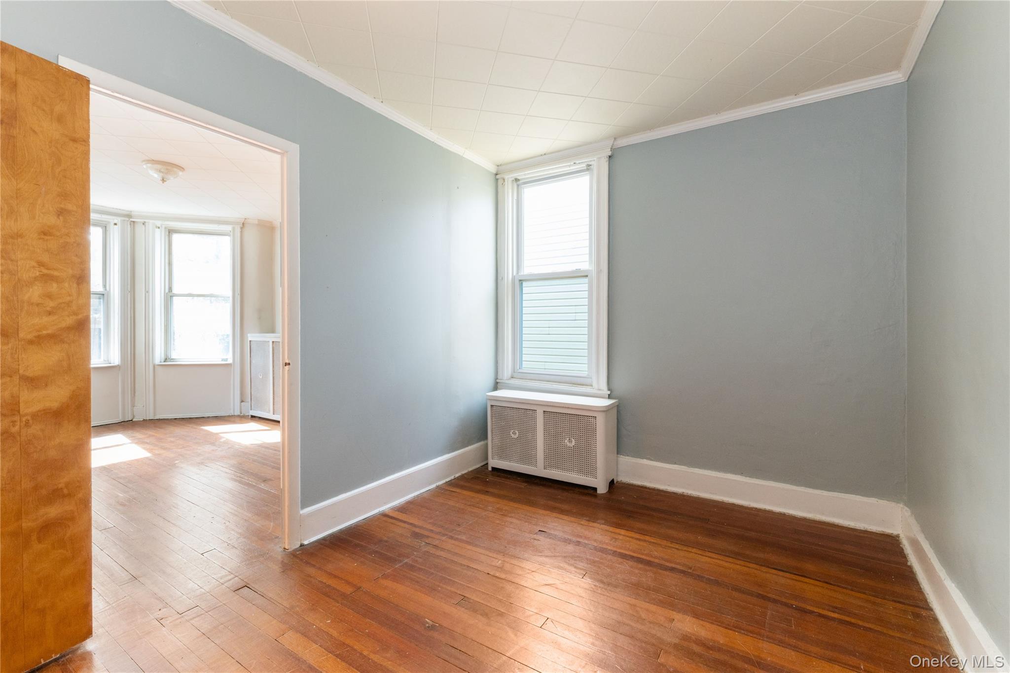 82-72 88th Place Queens, NY 11421 - Photo 17 of 26 an empty room with wooden floor and windows