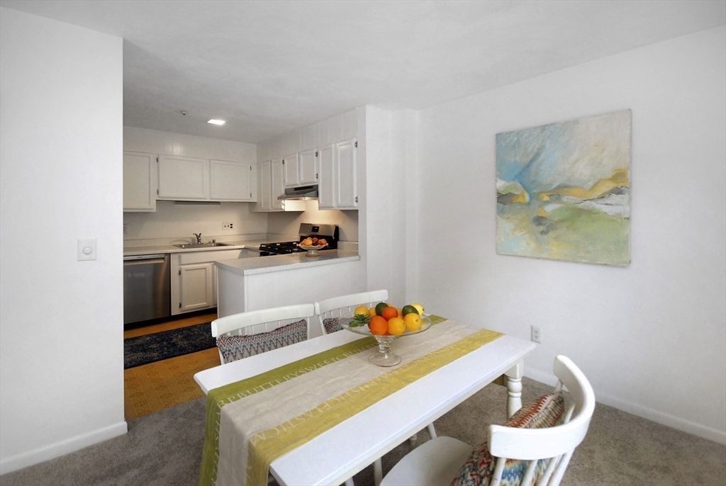 18 Concord Greene, Unit 6 Concord, MA 01742 - Photo 13 of 24 a kitchen with stainless steel appliances a dining table and chairs