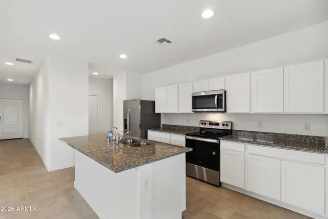 a kitchen with stainless steel appliances granite countertop a stove a sink and a refrigerator