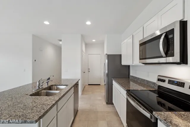 a kitchen with stainless steel appliances granite countertop a sink stove and microwave