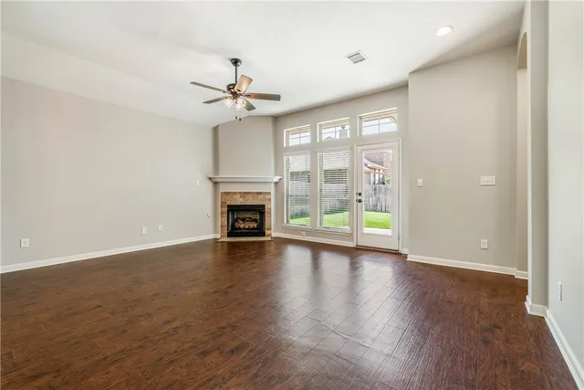 a view of an empty room with window a ceiling fan and wooden floor