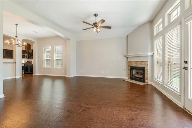 an empty room with wooden floor fireplace and windows