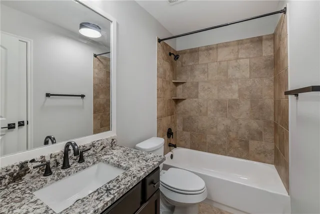 a bathroom with a granite countertop sink toilet and shower