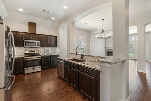 a kitchen with stainless steel appliances kitchen island granite countertop a sink stove and refrigerator