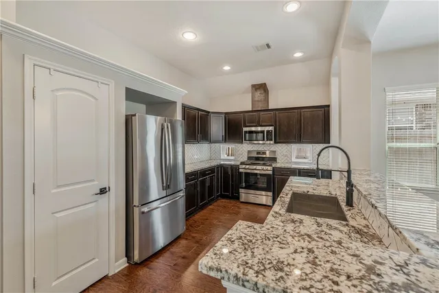 a kitchen with stainless steel appliances granite countertop a refrigerator sink and stove