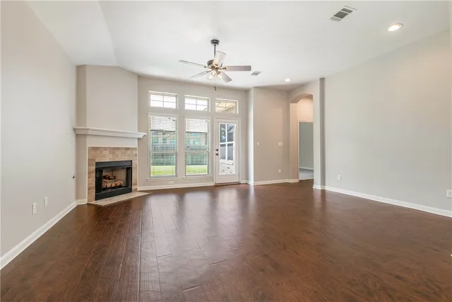 a view of an empty room with wooden floor fireplace and a window