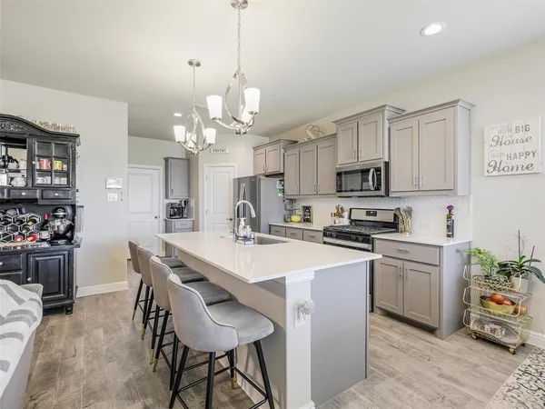 a kitchen with stainless steel appliances a table chairs sink and cabinets