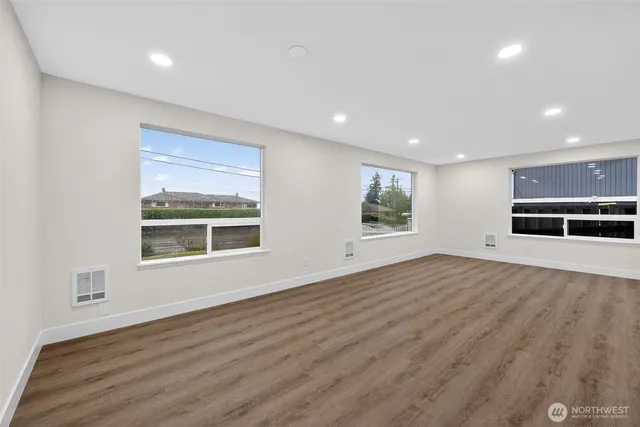 an empty room with wooden floor and windows