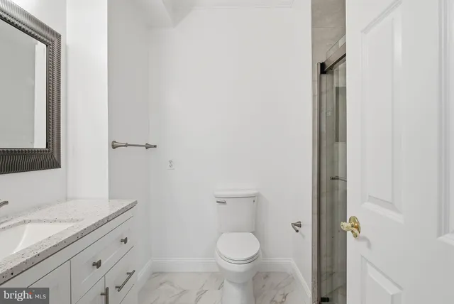 a bathroom with a granite countertop toilet a sink and mirror