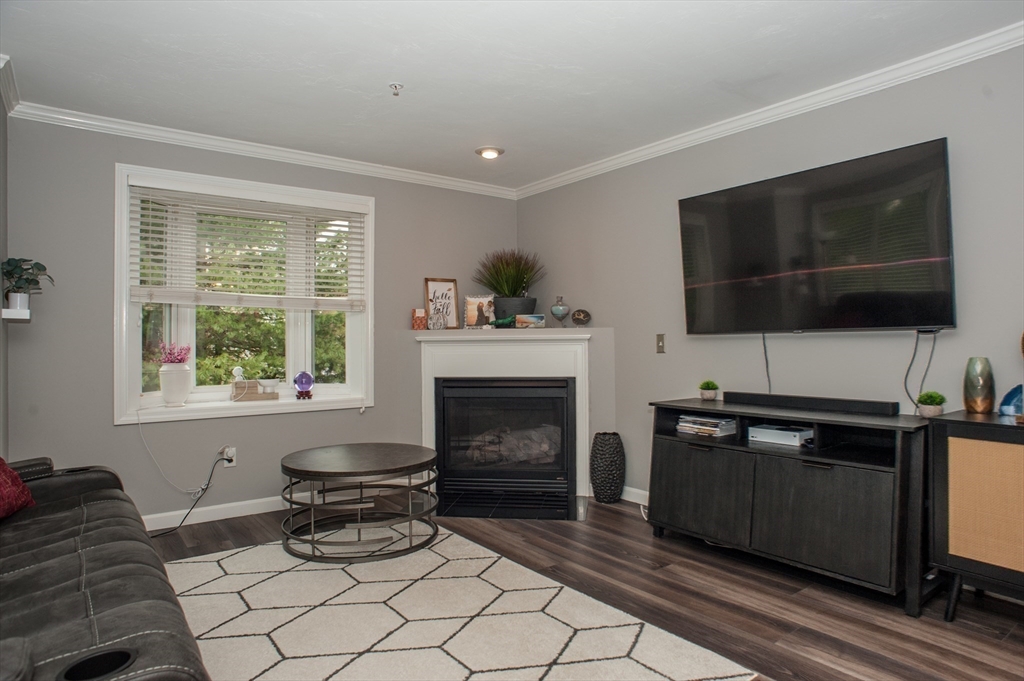 1501 Old Bridge Lane, Unit 1501 Bellingham, MA 02019 - Photo 9 of 42 a living room with furniture a flat screen tv and a fireplace