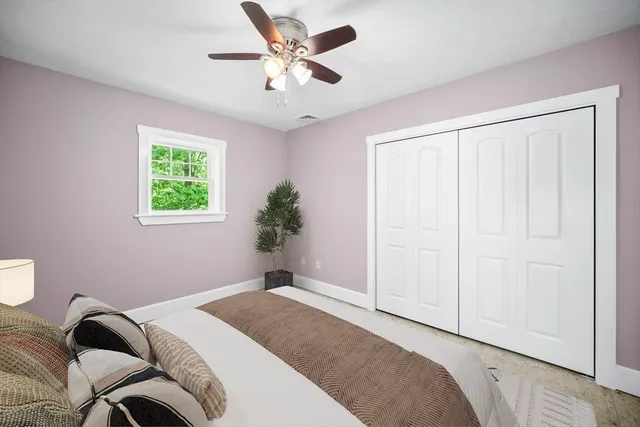 a bedroom with a bed ceiling fan and a window
