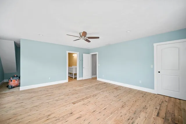 a view of an empty room with wooden floor and closet
