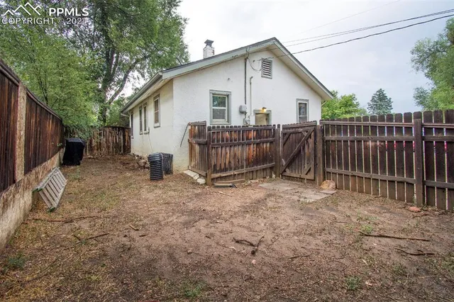 a view of a backyard with wooden fence and a large tree