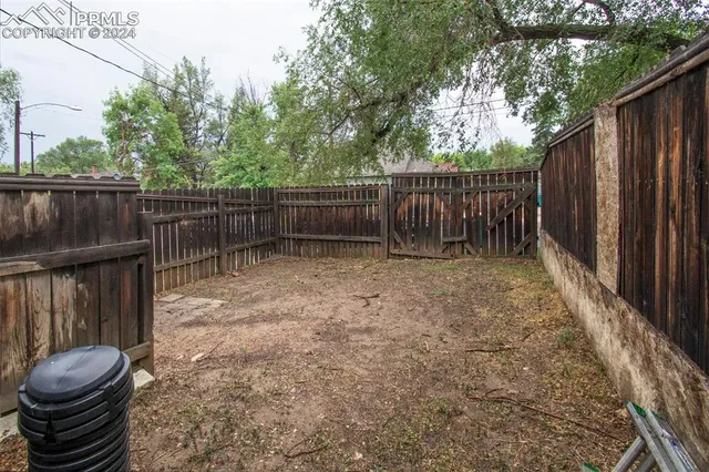a view of backyard with wooden fence and a large tree