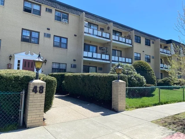 a front view of a building with garden and plants