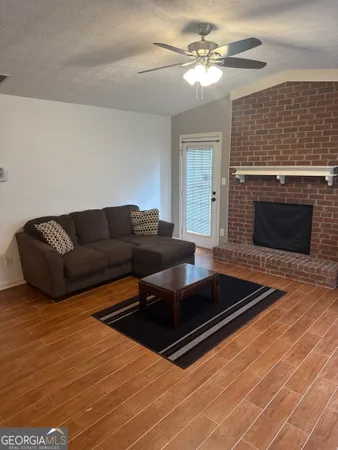 a living room with furniture a fireplace and a ceiling fan