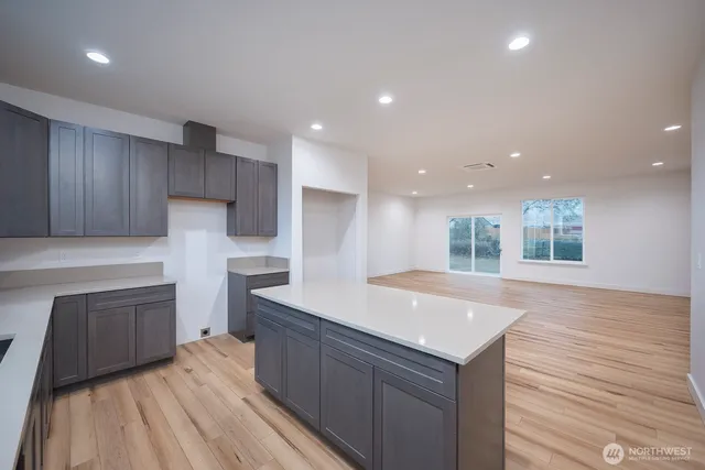 a kitchen with stainless steel appliances granite countertop a sink dishwasher a stove and a refrigerator with wooden floor