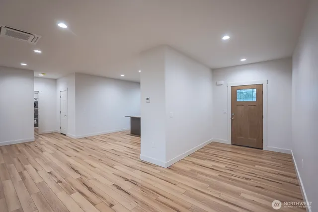 a view of an empty room with wooden floor and closet