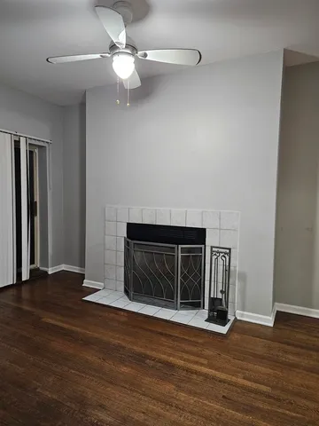 a view of an empty room with wooden floor fireplace and a window