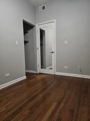 a view of an empty room with wooden floor and closet