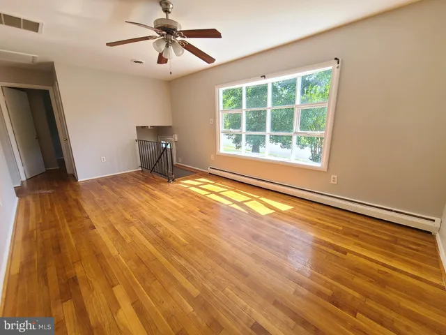 a view of an empty room with windows and chandelier fan