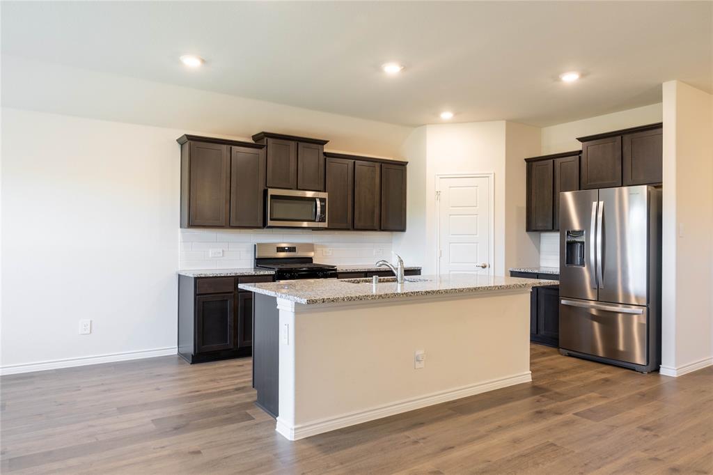 419 Revolution Road Fate, TX 75189 - Photo 3 of 19 Kitchen featuring stainless steel appliances, light stone countertops, dark brown cabinets, dark wood-type flooring, and recessed lighting