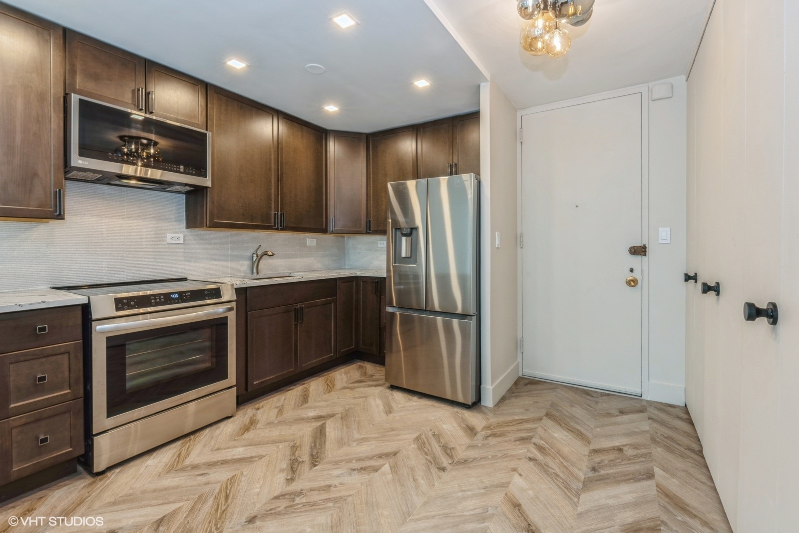 720 West Gordon Terrace, Unit 4M Chicago, IL 60613 - Photo 4 of 10 a kitchen with stainless steel appliances granite countertop a refrigerator a stove and a sink with wooden floor